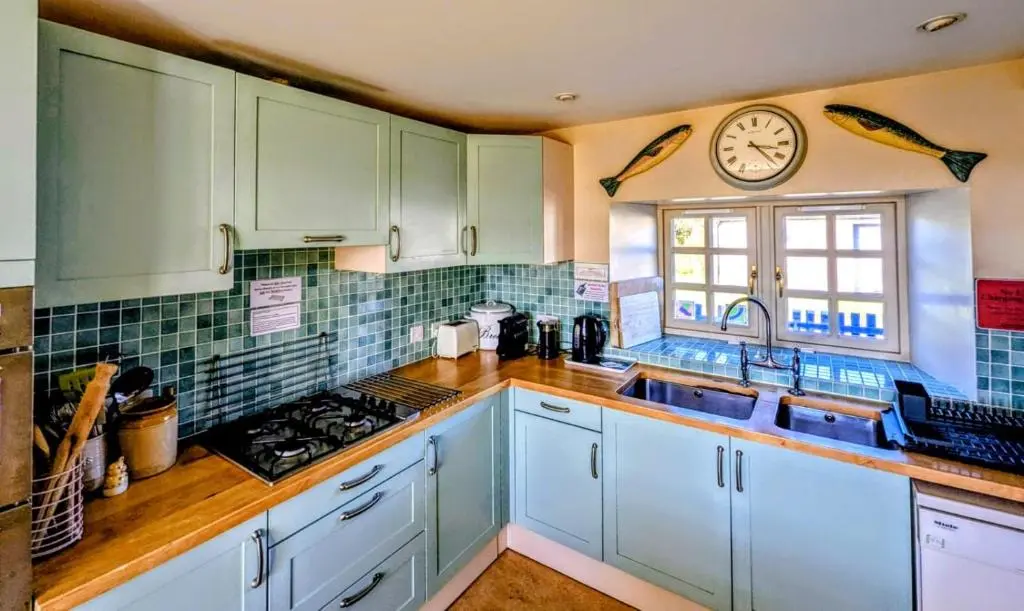 a kitchen with white cabinets and a clock on the wall at Reids Cottage in Lairg