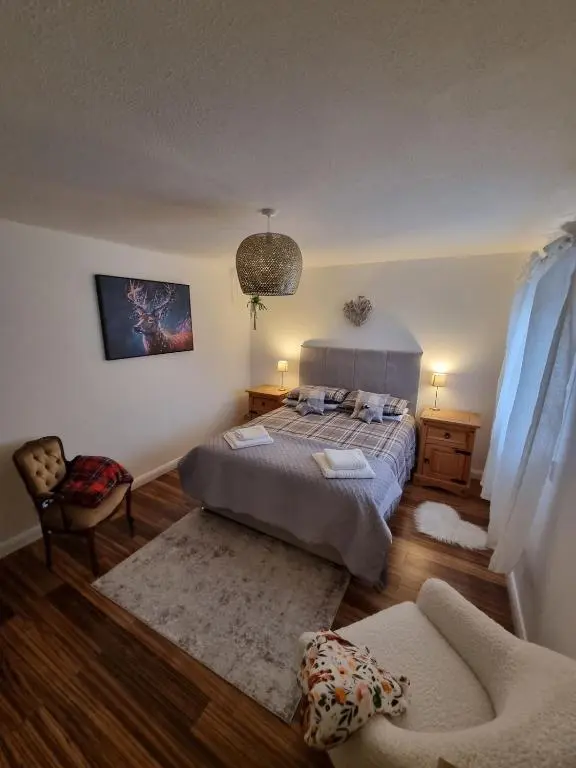 a bedroom with a bed and a chair and a couch at Highland Breeze Inverness in Inverness