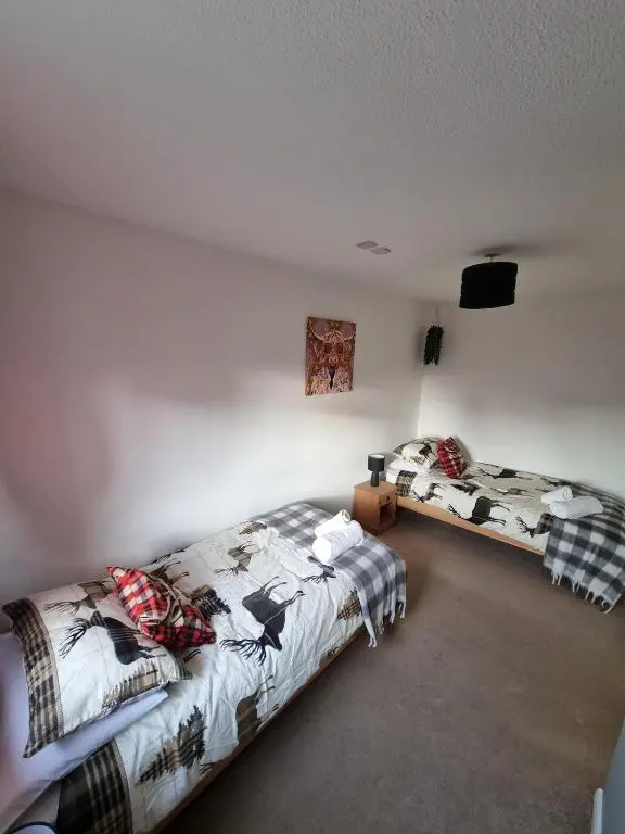 two beds in a room with a wall at Highland Breeze Inverness in Inverness