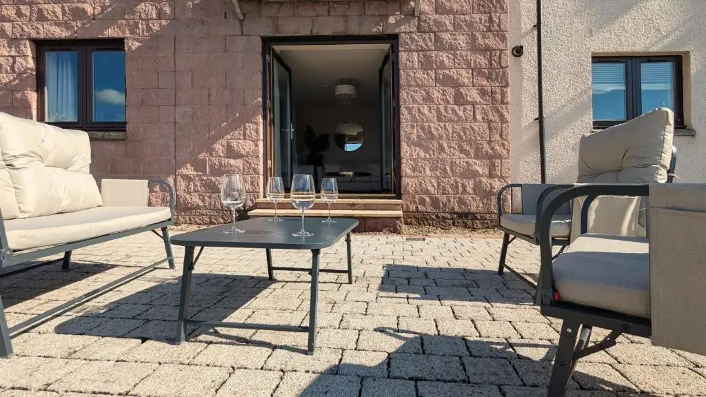 a patio with two chairs and a table with wine glasses on it at The Wee Heilan' Drochaid in Inverness