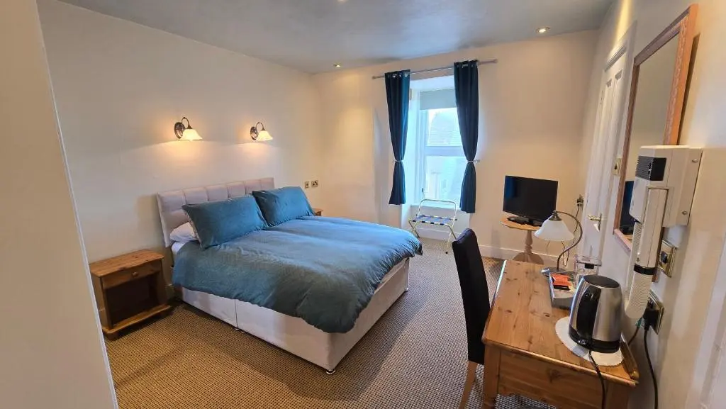 a bedroom with a bed and a desk with a computer at The Pitfour Arms Hotel in Mintlaw