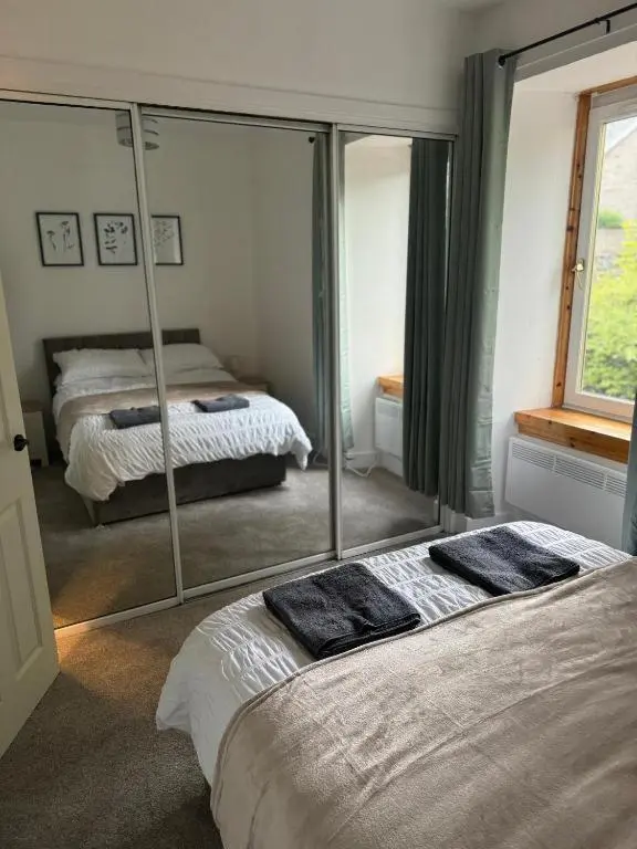 a bedroom with two beds and a large mirror at Stephen's Brae Apartment, Inverness City Centre in Inverness