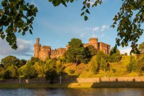a castle sitting on top of a hill next to a lake at Stephen's Brae Apartment, Inverness City Centre in Inverness
