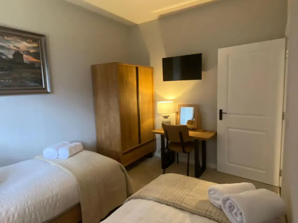 a room with two beds and a desk with a computer at travelNess Apartment in Inverness