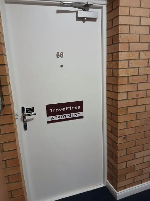 a white door with a sign on it next to a brick wall at travelNess Apartment in Inverness