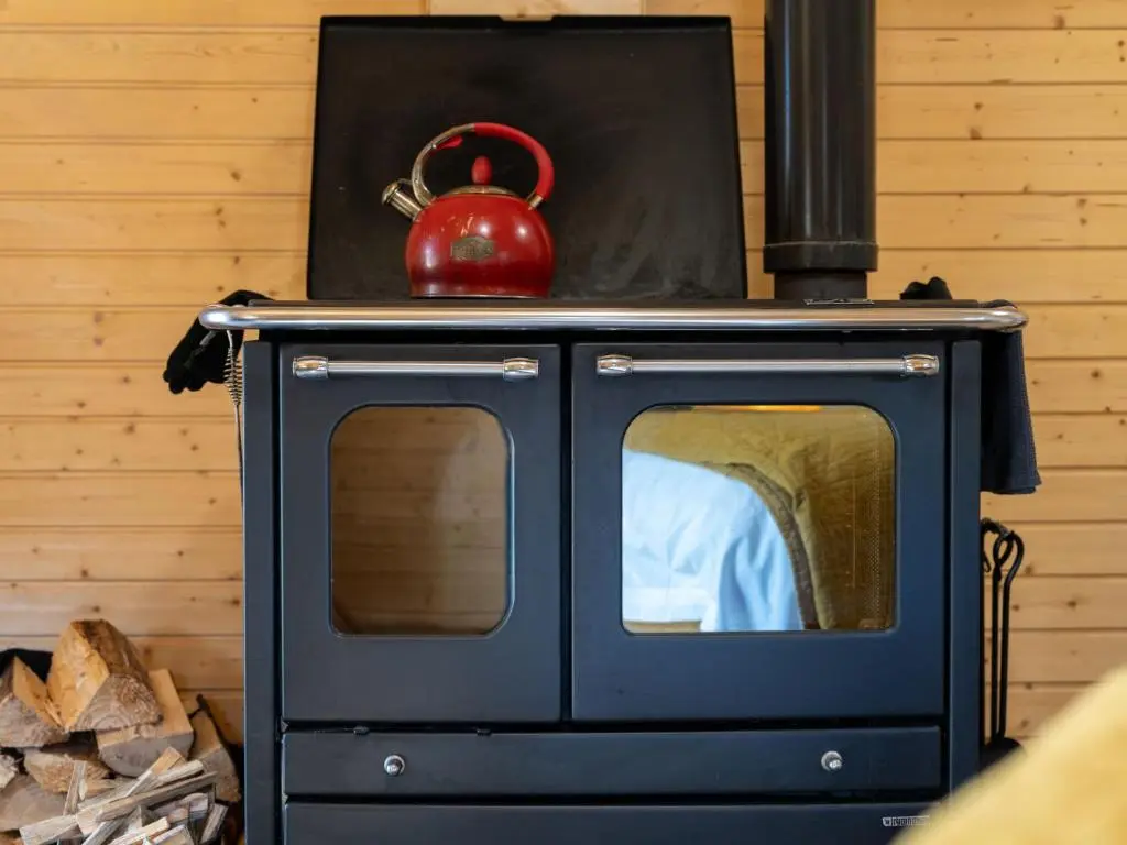 a blue stove with a red tea kettle on top at Apartment Ghillie's Bothy by Interhome in Coldstone