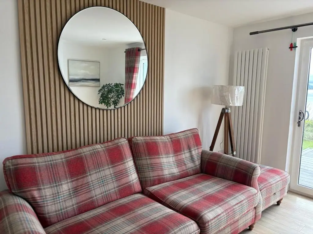a living room with a couch and a mirror at Seaside Retreat - Quiet Seafront Spot with Free Parking in North Kessock