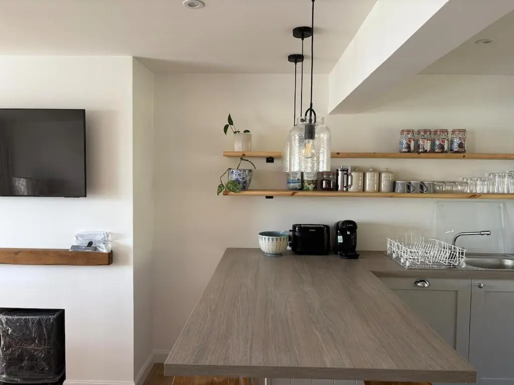 a kitchen with a wooden table and a tv at Seaside Retreat - Quiet Seafront Spot with Free Parking in North Kessock