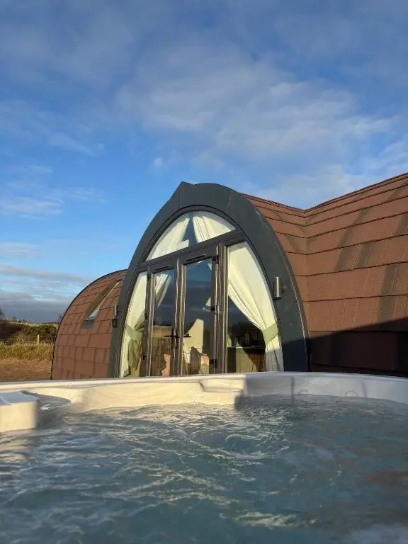 a circular building with a swimming pool in front of it at Dornoch Pods in Dornoch