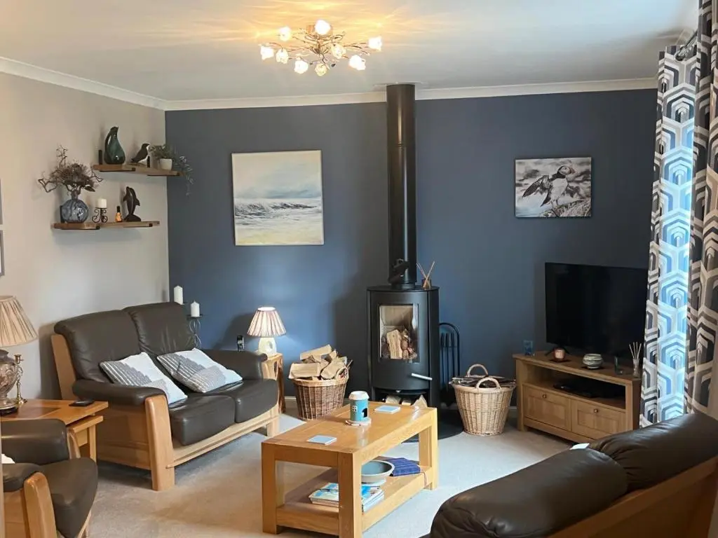 a living room with a couch and a tv at Lighthouse Cottage Cullen in Cullen