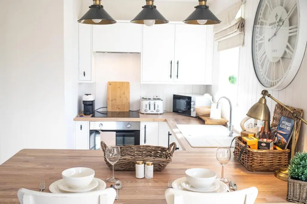 a kitchen with a table with chairs and a clock on the wall at Lillymont Apartment - Inverness City Centre in Inverness