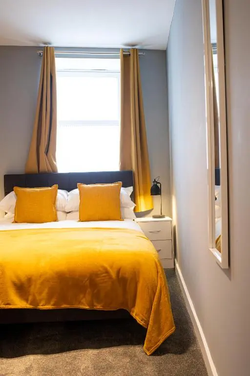 a bedroom with a yellow bed with a window at Baron Taylor Stays in Inverness