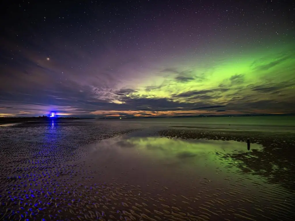 a green light in the sky over a beach at night at Whispering Dunes - Silver Sands Holiday Park in Lossiemouth