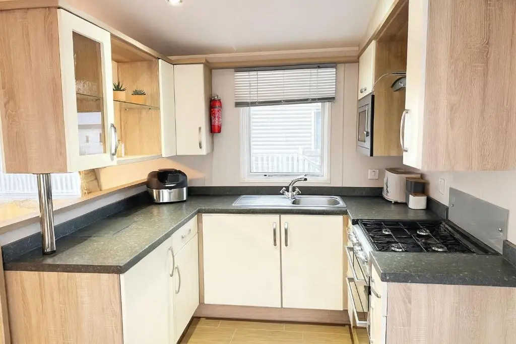 a kitchen with white cabinets and a sink at Whispering Dunes - Silver Sands Holiday Park in Lossiemouth