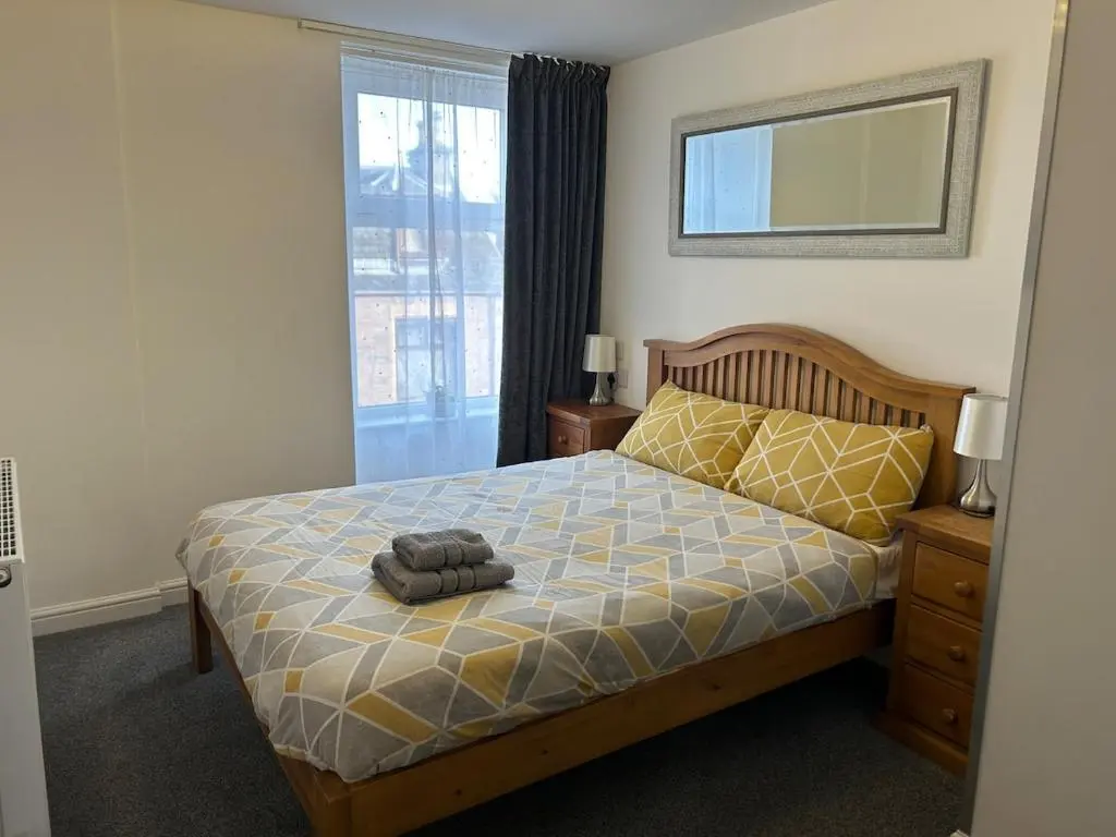 a bedroom with a bed and a mirror and a window at Chloes Holiday Apartments in Inverness