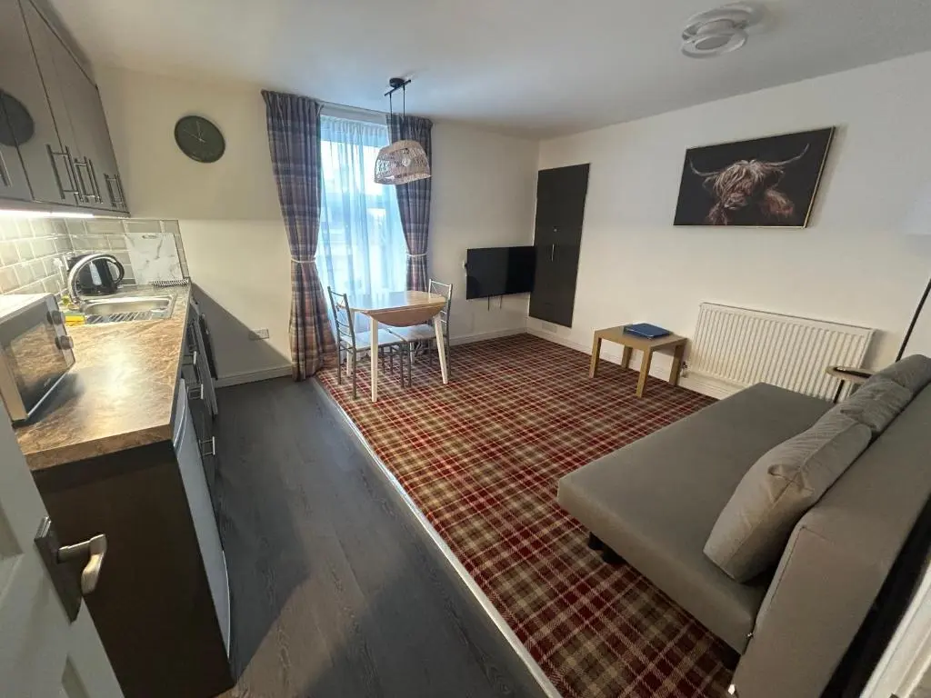 a small living room with a couch and a kitchen at Chloes Holiday Apartments in Inverness
