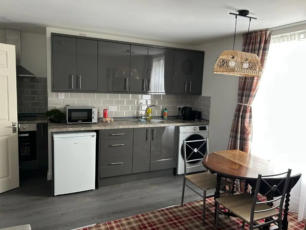 a kitchen with gray cabinets and a table and a table and chairs at Chloes Holiday Apartments in Inverness