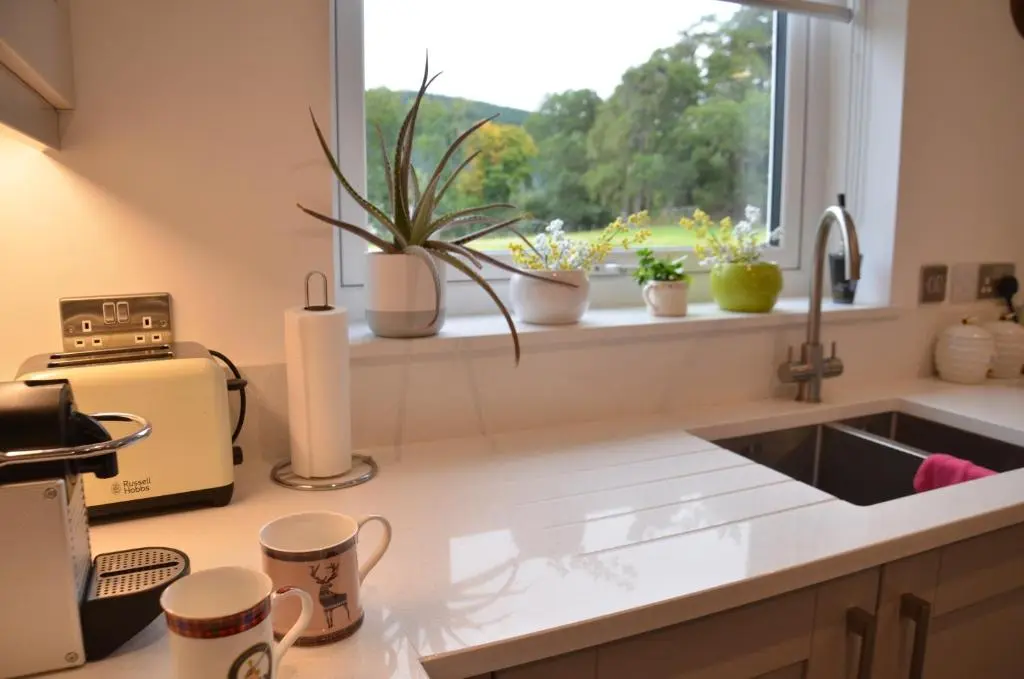 a kitchen with a sink and a window with potted plants at Fionnlagh Cottage in Eskadale