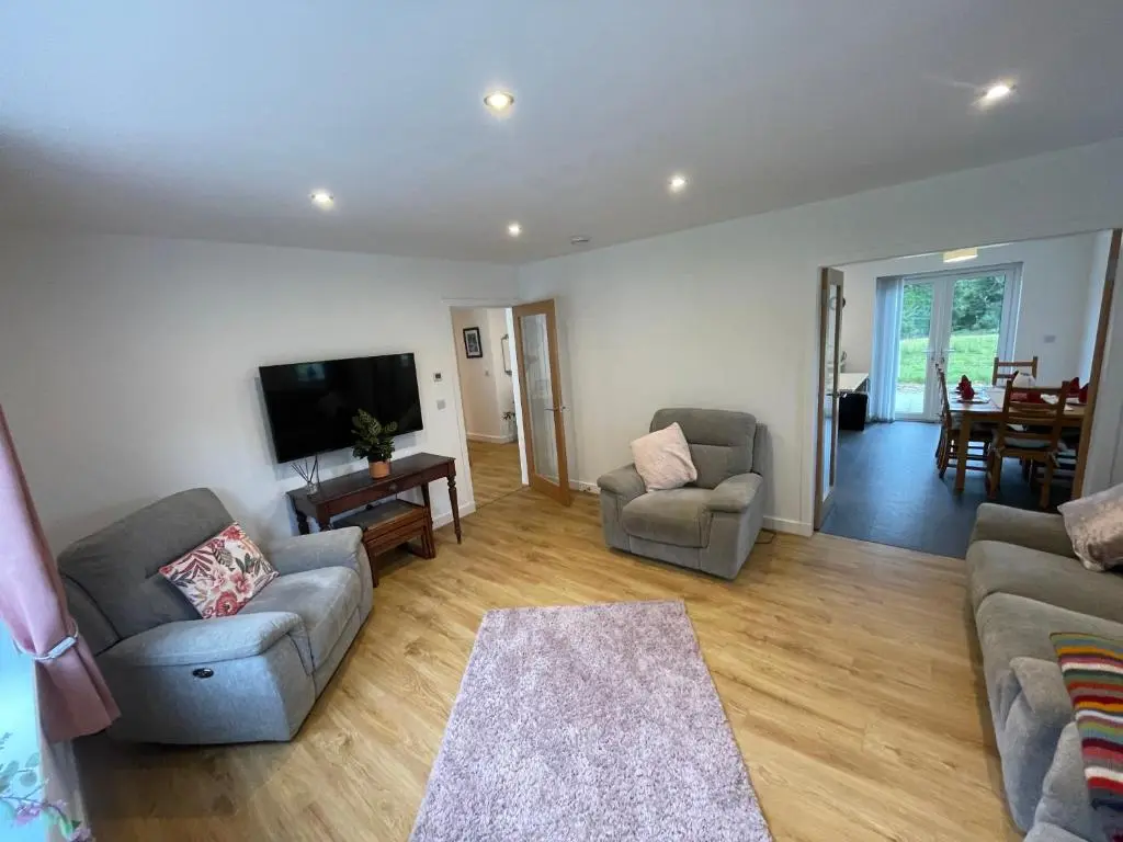 a living room with two couches and a flat screen tv at Fionnlagh Cottage in Eskadale