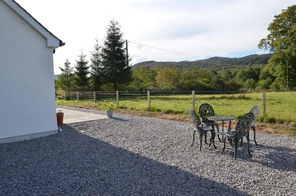 a table and four chairs sitting on a gravel patio at Fionnlagh Cottage in Eskadale