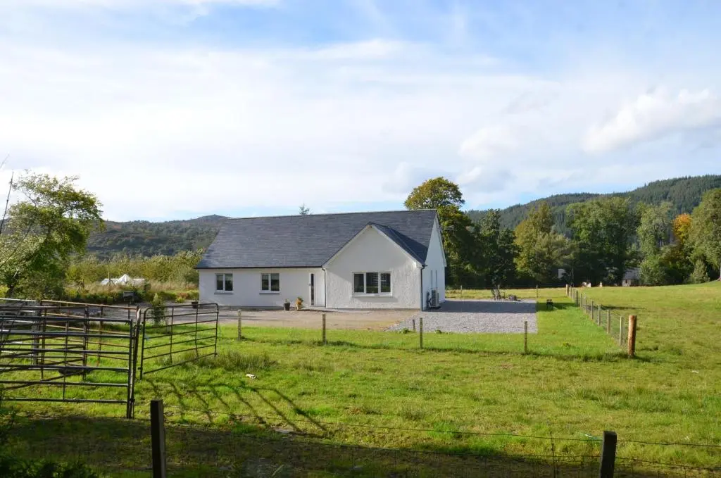 a white house in the middle of a field at Fionnlagh Cottage in Eskadale