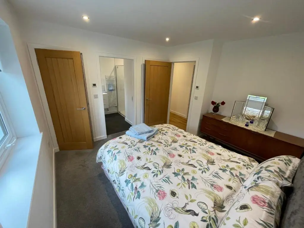 a bedroom with a bed and a dresser and mirror at Fionnlagh Cottage in Eskadale