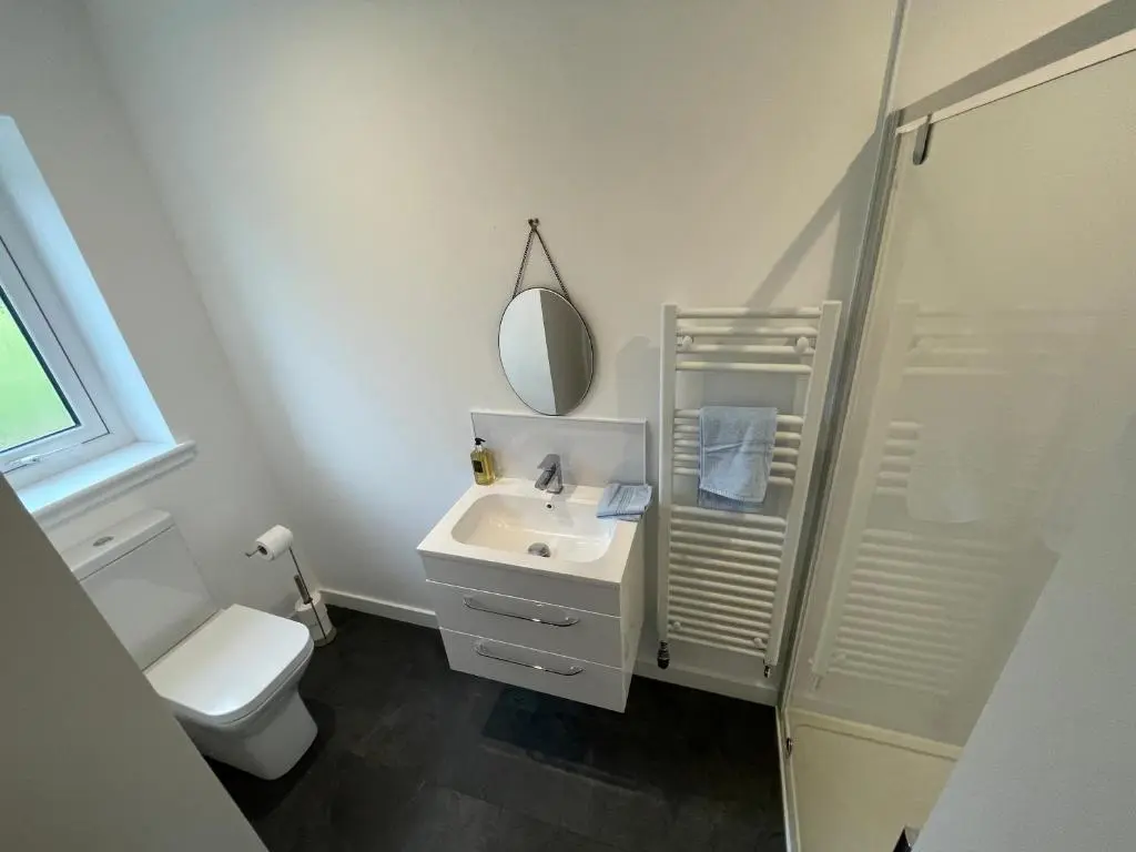 a bathroom with a sink and a toilet and a mirror at Fionnlagh Cottage in Eskadale