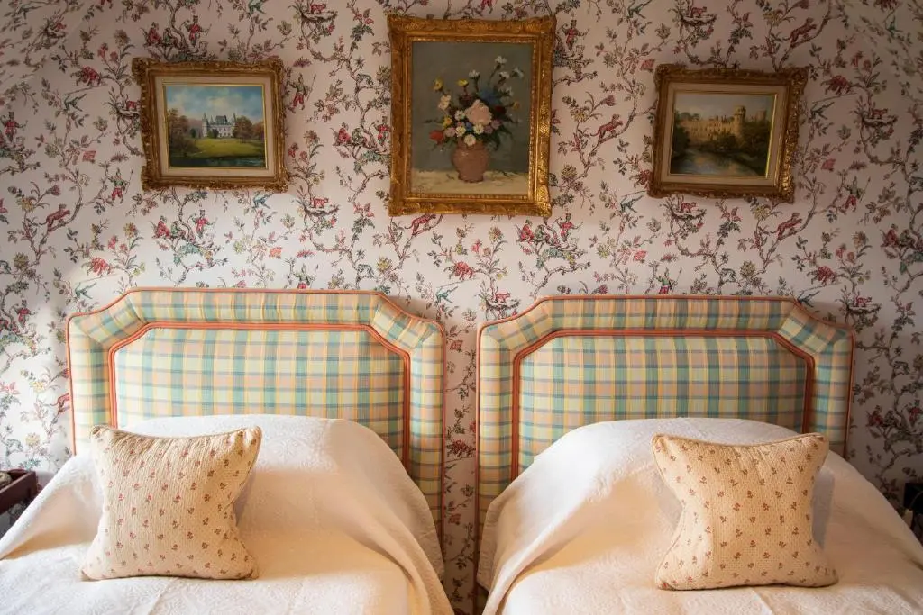 two beds in a room with wallpaper at Grieves Cottage Balnagown Estate in Kildary