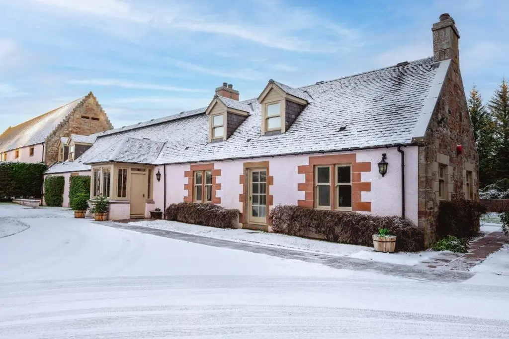 a house in the snow with a driveway at Grieves Cottage Balnagown Estate in Kildary