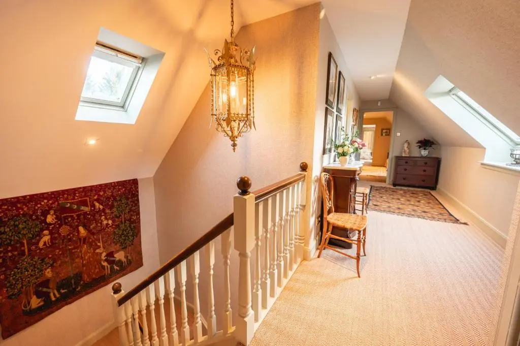 a hallway with a staircase with a chandelier at Grieves Cottage Balnagown Estate in Kildary