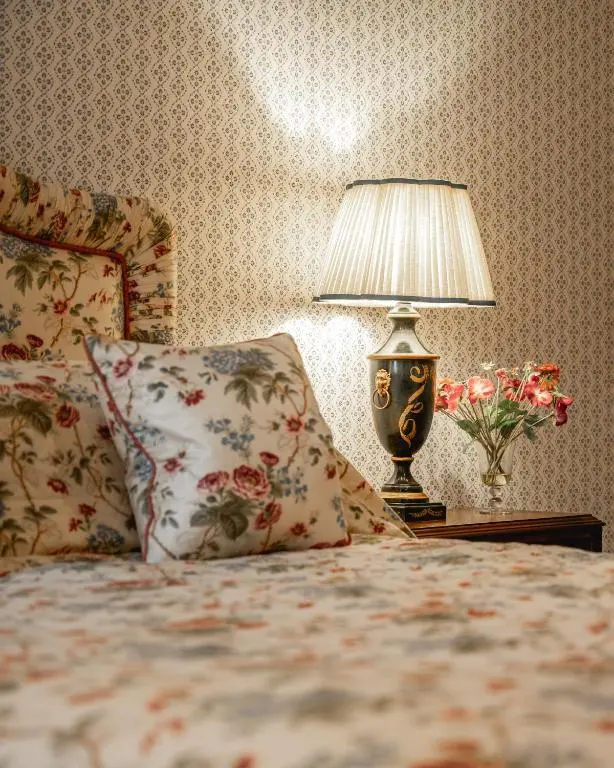 a bedroom with a bed with a lamp and flowers at Grieves Cottage Balnagown Estate in Kildary