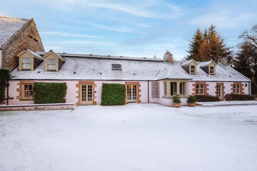 a large white house with a driveway in the snow at Grieves Cottage Balnagown Estate in Kildary