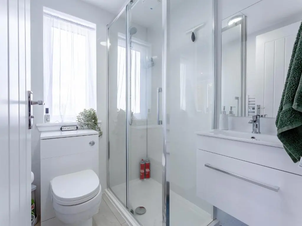 a white bathroom with a toilet and a shower at Charlies Cottage in Inverness