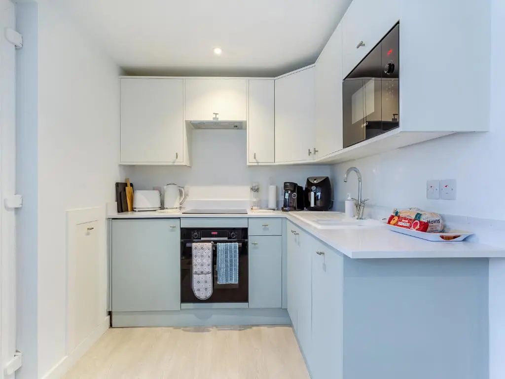a kitchen with white cabinets and a blue oven at Charlies Cottage in Inverness