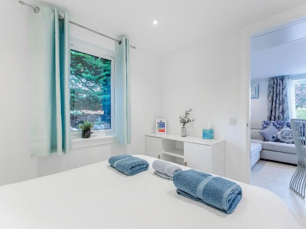 a white bedroom with two pillows on a bed at Charlies Cottage in Inverness