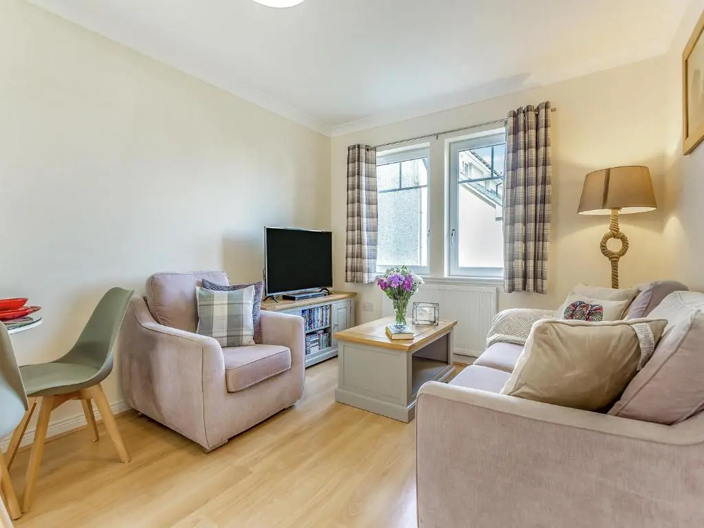 a living room with two chairs and a tv at Kincraig Apartment in Inverness