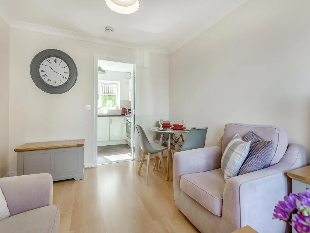 a living room with a chair and a clock on the wall at Kincraig Apartment in Inverness