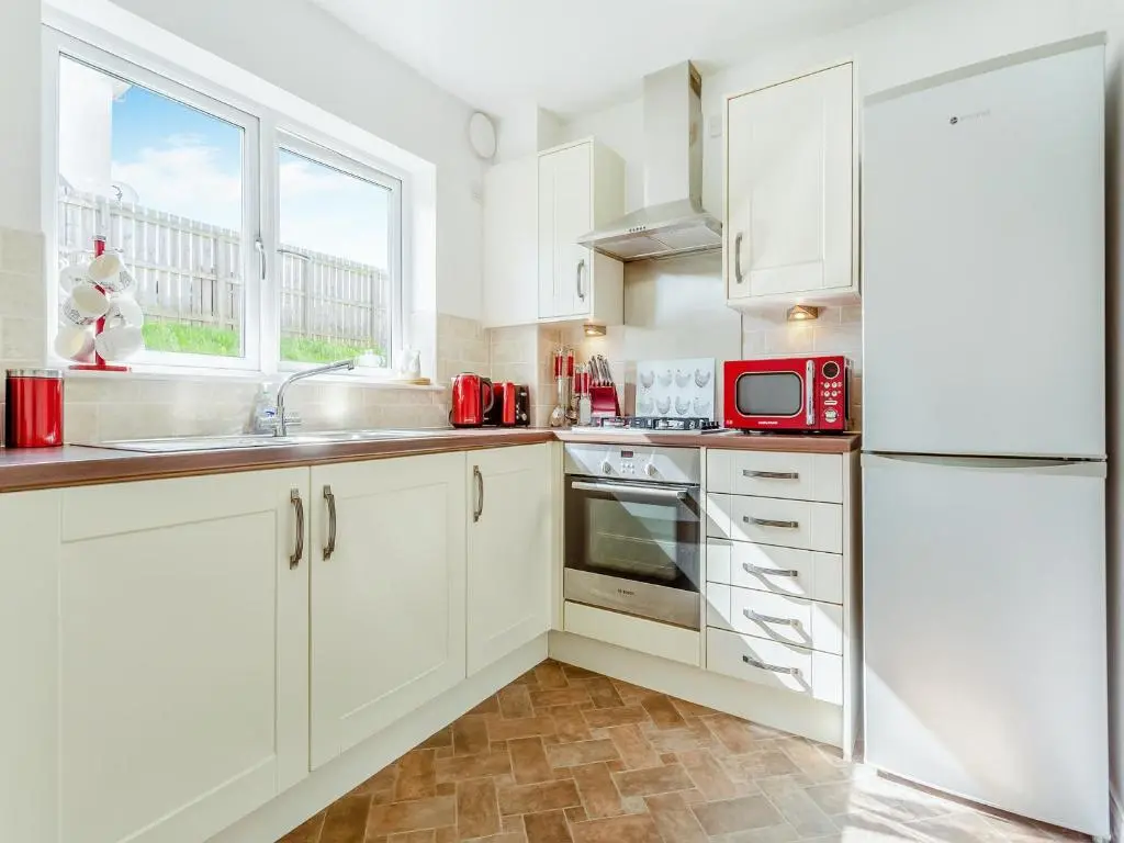 a white kitchen with a sink and a refrigerator at Kincraig Apartment in Inverness