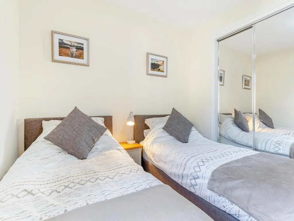 two twin beds in a bedroom with a mirror at Kincraig Apartment in Inverness
