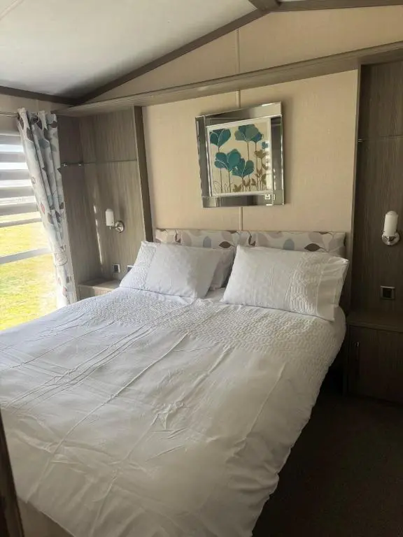 a large white bed in a room with a window at Spacious Modern Seaside Caravan in Lossiemouth