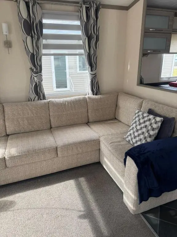 a couch in a living room with a window at Spacious Modern Seaside Caravan in Lossiemouth
