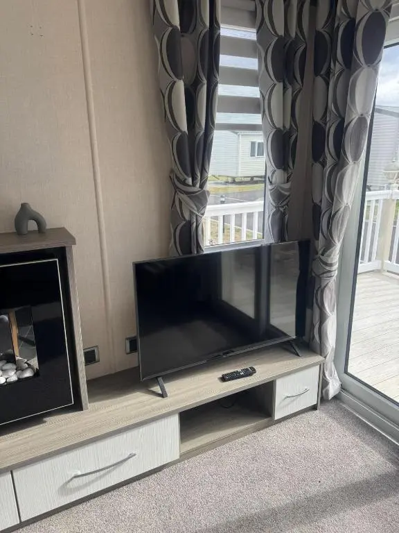 a flat screen tv sitting on a entertainment center in a living room at Spacious Modern Seaside Caravan in Lossiemouth