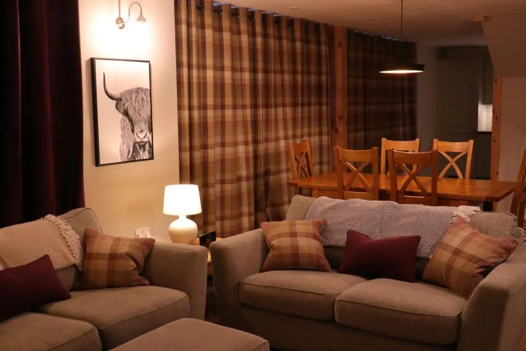 a living room with two couches and a dining room at Remore Steading - Coachhouse in Ardclach