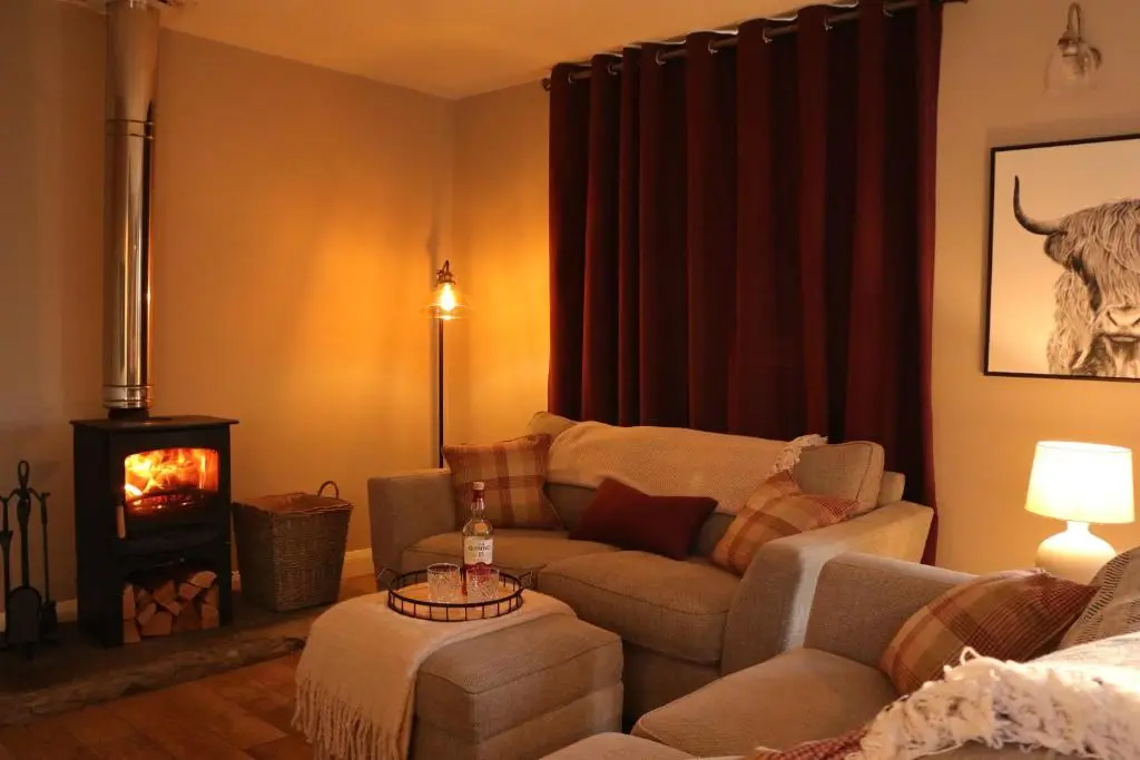 a living room with a couch and a fire place at Remore Steading - Coachhouse in Ardclach