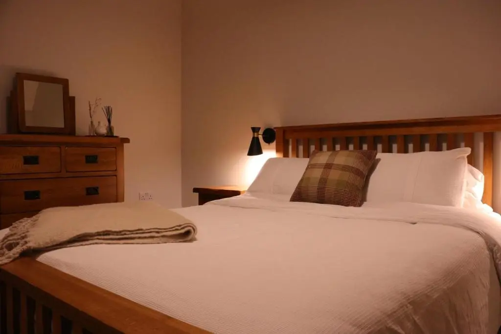 a bedroom with a white bed with a dresser and a mirror at Remore Steading - Coachhouse in Ardclach