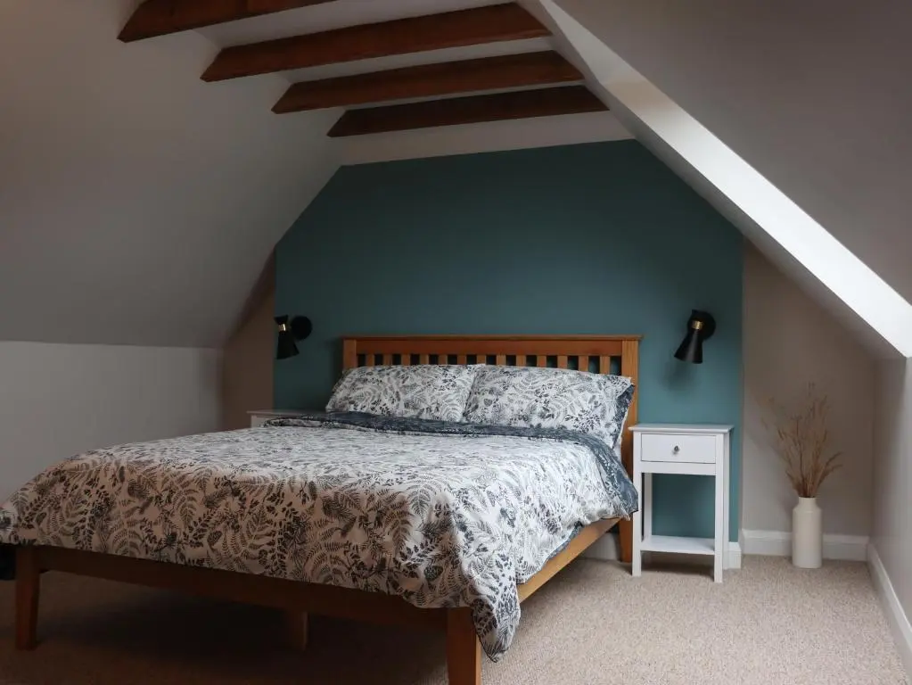 a bedroom with a bed and a blue wall at Remore Steading - Coachhouse in Ardclach