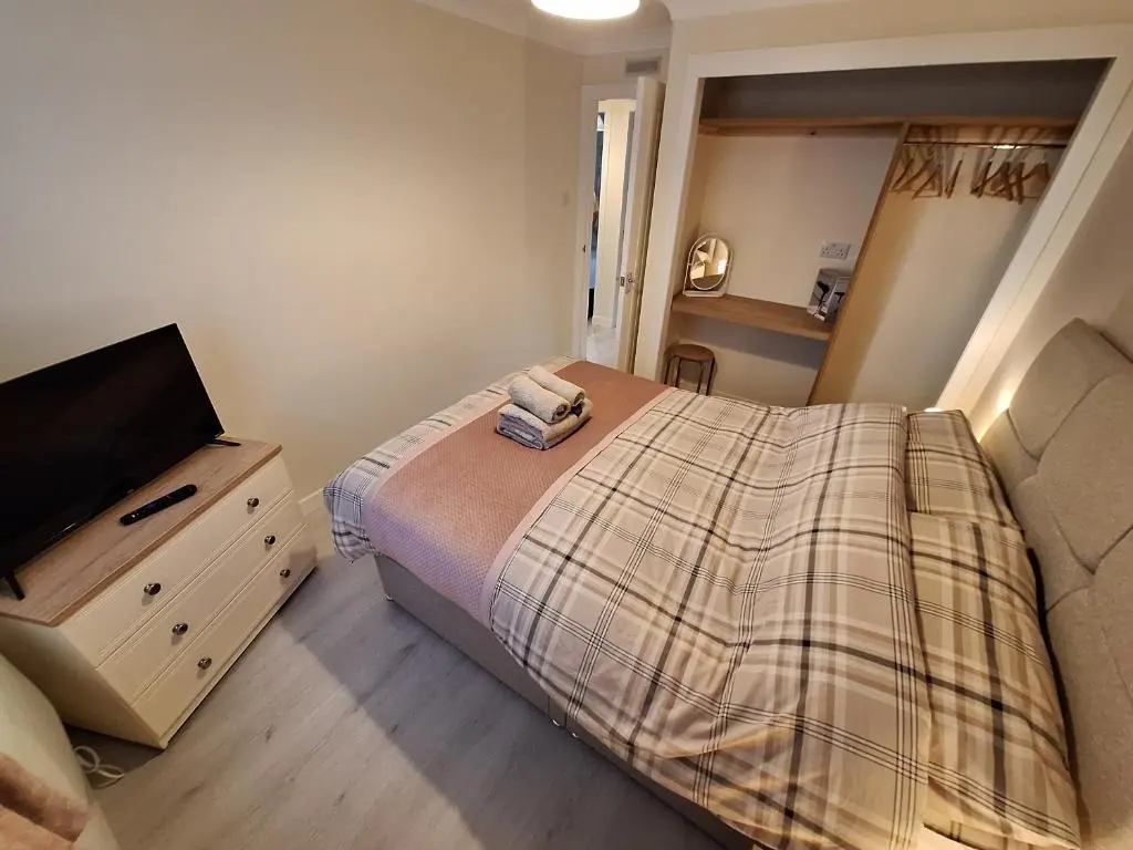 a bedroom with a bed and a flat screen tv at Modern Two Bed City Apartment!! in Inverness