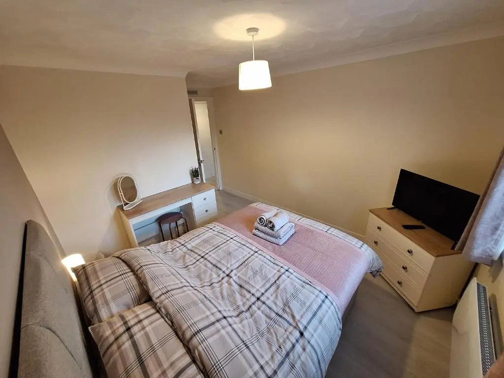a bedroom with a bed and a dresser and a television at Modern Two Bed City Apartment!! in Inverness