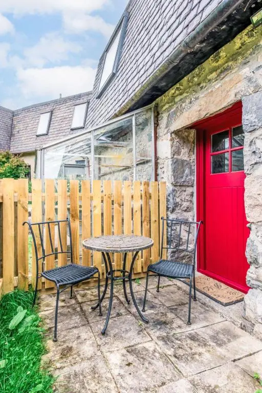a table and chairs on a patio with a red door at Holiday Home Highland Garden Room by Interhome in Drumnadrochit