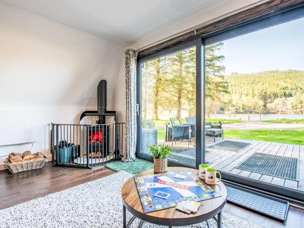 a living room with a table and a fireplace at Chalet Pine Needle Lodge by Interhome in Spean Bridge